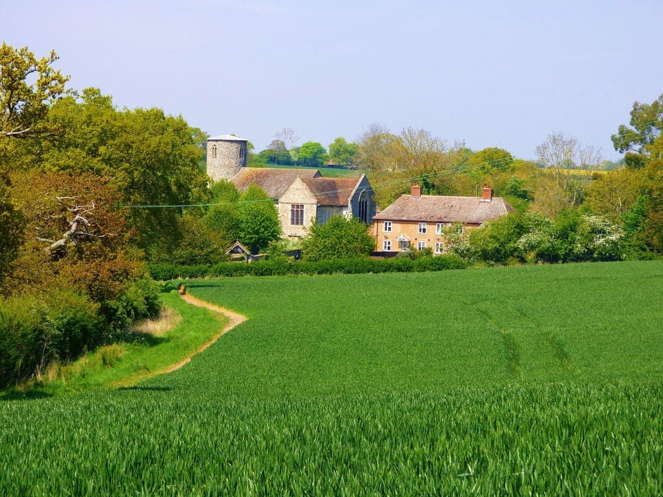 View of cottage and church from fields to the front
