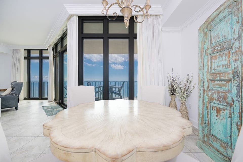 Bright dining area featuring a unique wooden table, elegant chairs, and stunning views through large windows
