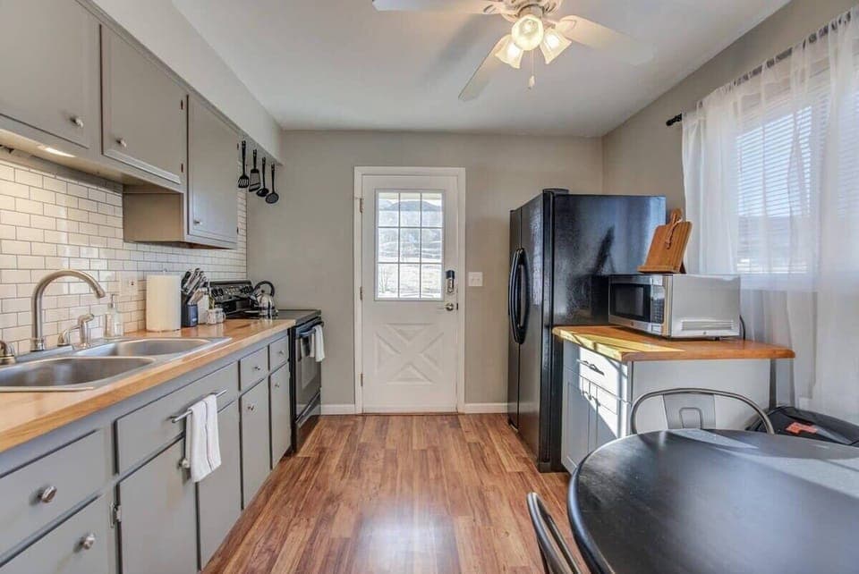 Cook and chat in the bright, galley-style kitchen with gray cabinetry, subway-tile backsplash, and a full stove for home-style meals.