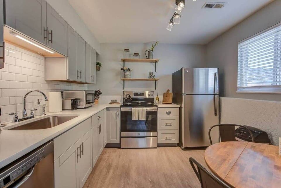 Cook and chat in the clean, bright kitchen with white cabinetry, subway-tile backsplash, and stainless appliances—plus a small table for casual bites.
