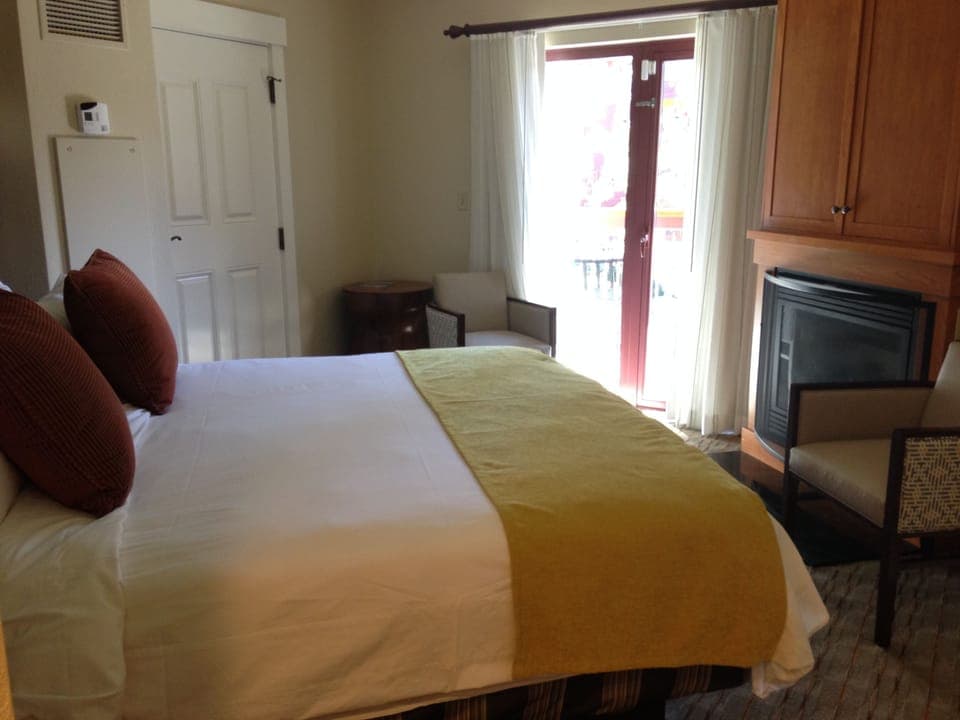 Fireplace at end of bed with TV behind cabinet doors above fireplace