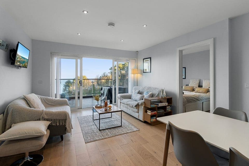 Light and contemporary living area with full width sliding doors opening onto the large balcony.