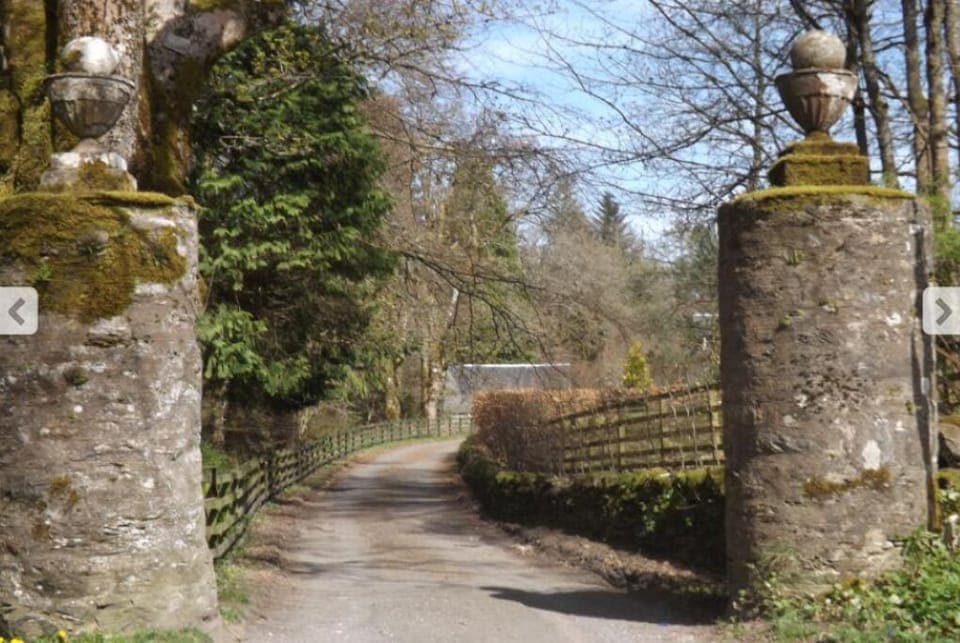 Cottage roof just visible through historic pillars at entrance to estate.