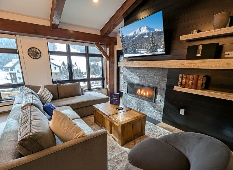 Sink into the plush sofa by the cozy fireplace, surrounded by mountain views