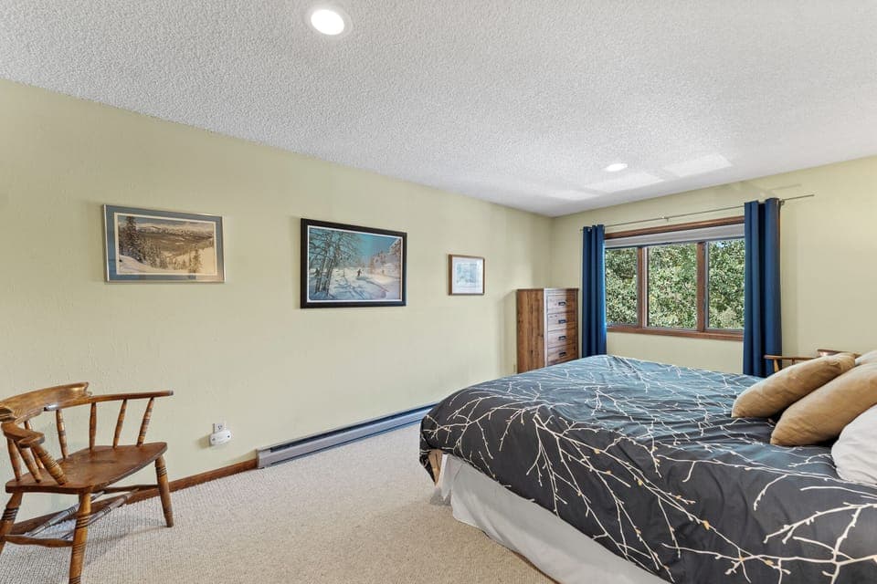 Upstairs guest bedroom featuring a king-sized bed and large windows.