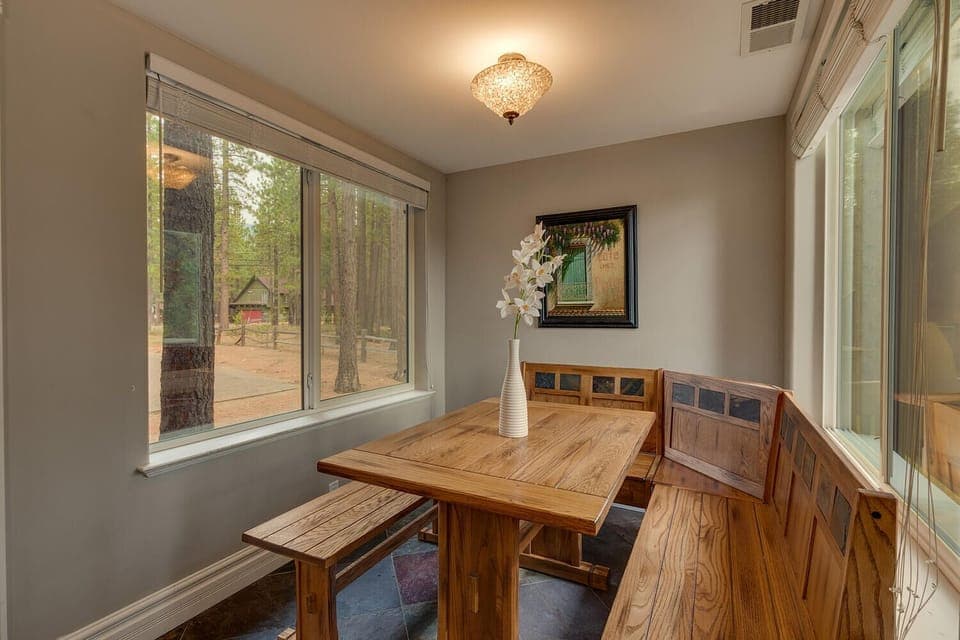 - Cozy breakfast nook with wood benches  
- Surrounded by large windows and forest views  
- Mountain cabin charm with rustic dining