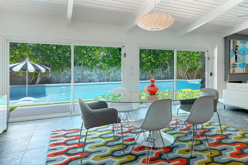 Swanky dining room with marble tulip table with view of yard and sparkling pool
