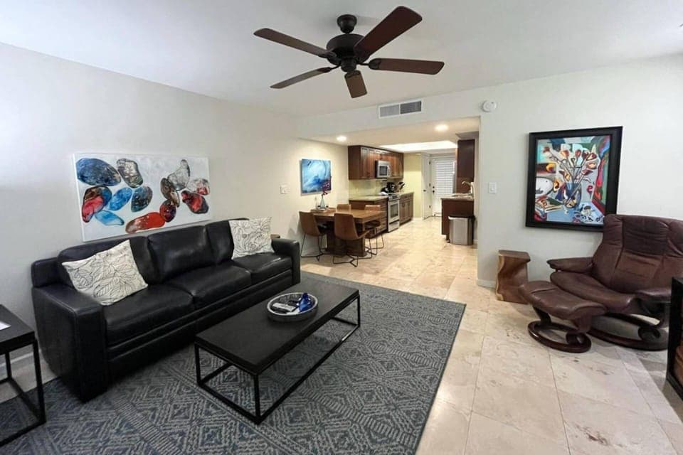 Living room with sofa, TV and doors to the back patio with outdoor furniture