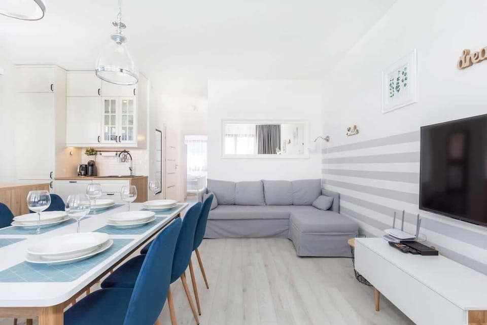 An open-concept living room with a sofa, dining area, and large windows, giving a spacious and comfortable feel.