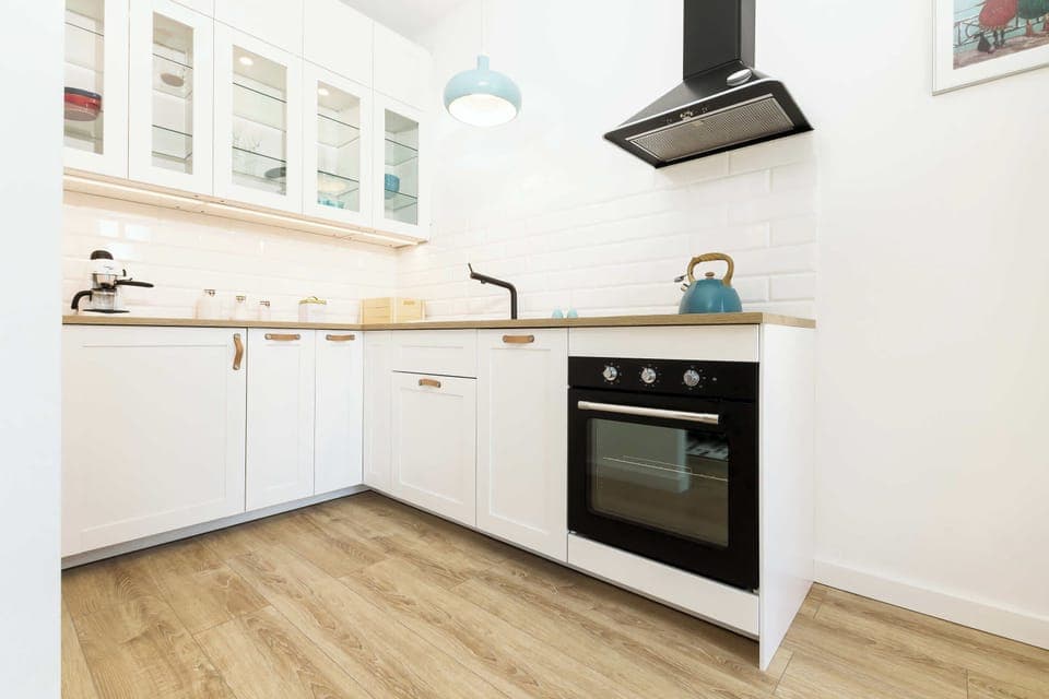 A closer look at the kitchen, showcasing sleek white cabinets, a built-in oven, and a tiled backsplash. The space is both functional and stylish.