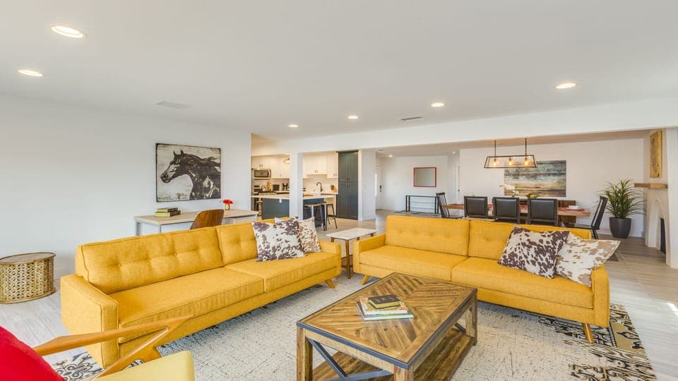 - Open living area with yellow sofas and wood accents   - Seamless flow into dining and kitchen gathering   - Central hub for relaxing, entertaining, and fun