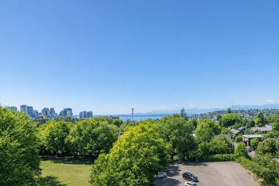 Scenic city and mountain views overlooking lush green parkland, offering a peaceful outlook with urban skyline in the distance.
