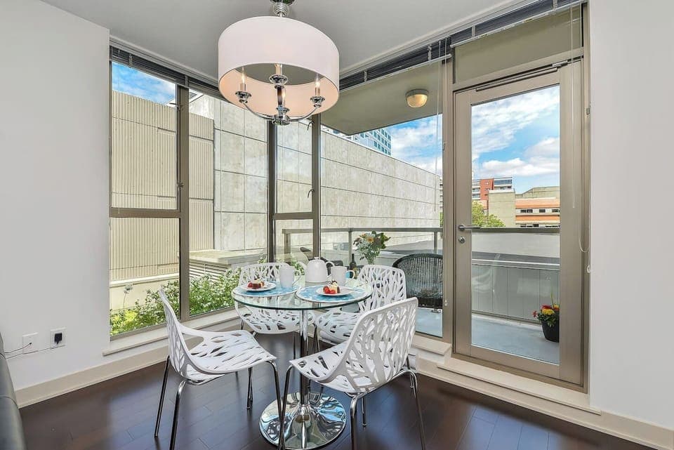 Dining table seats 4 surrounded by floor to ceiling windows and private balcony