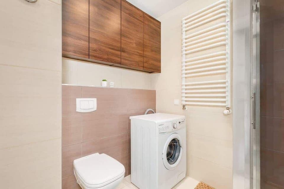 Bright bathroom with washing machine and shower cabin. 