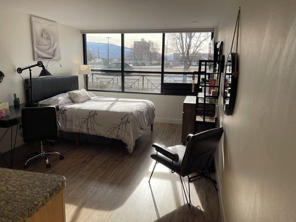 Queen bed, facing the TV, with dresser, and shelves on either side of the dresse