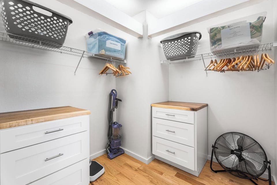 Your spacious walk-in closet offers ample storage with built-in shelving, wooden hangers, and organized drawers for all your belongings.
