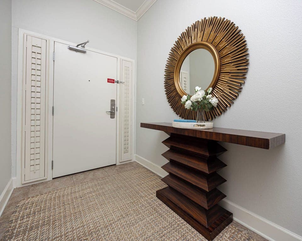 This welcoming entryway features a stylish console table and a striking sunburst mirror, setting a warm tone for your stay