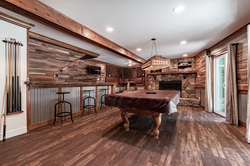 Large game room with pool table, card table, a bar, TV and pullout sofa. 