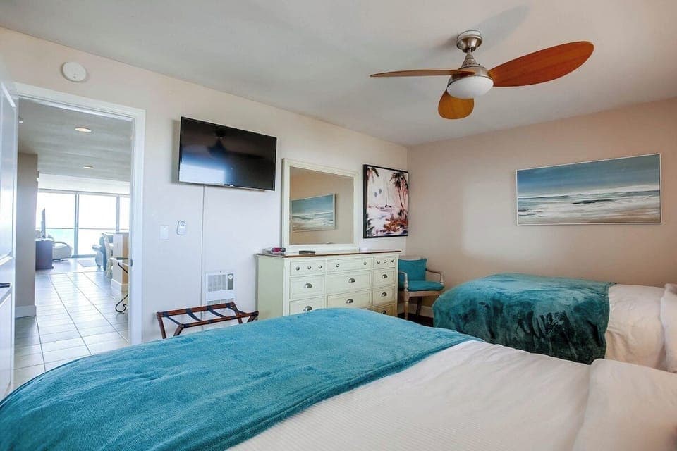 Guest bedroom with dresser, TV, ceiling fan, mirrored closet, and 2 queen size beds