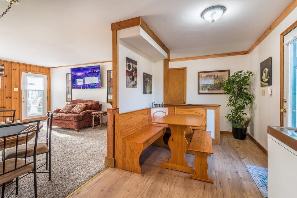 Corner dining nook with pine bench seating and matching table on wood-look laminate floors.