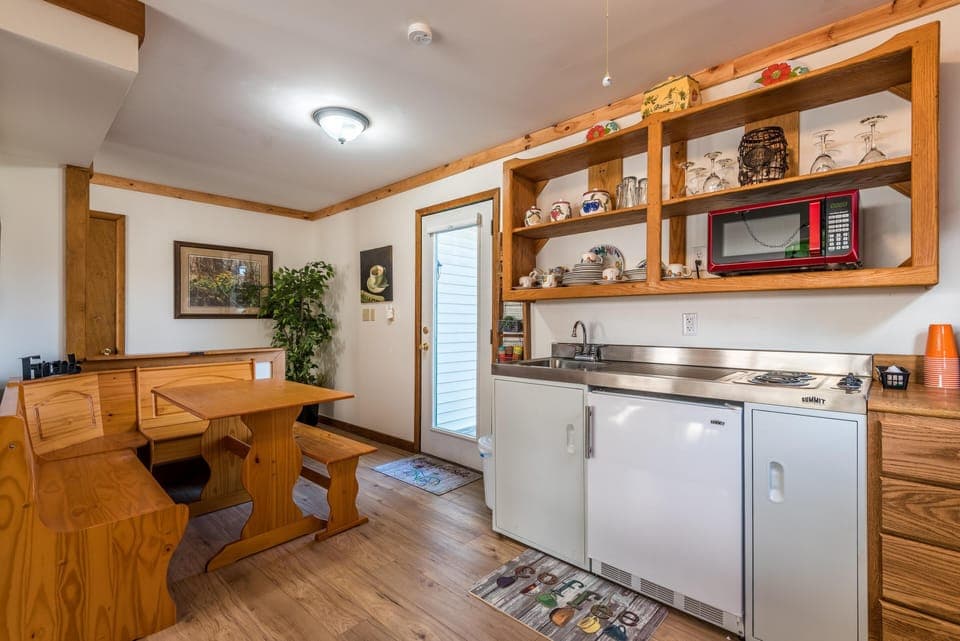 Kitchen nook with built-in pine bench seating, open wooden shelves, and stainless steel sink and cooktop.