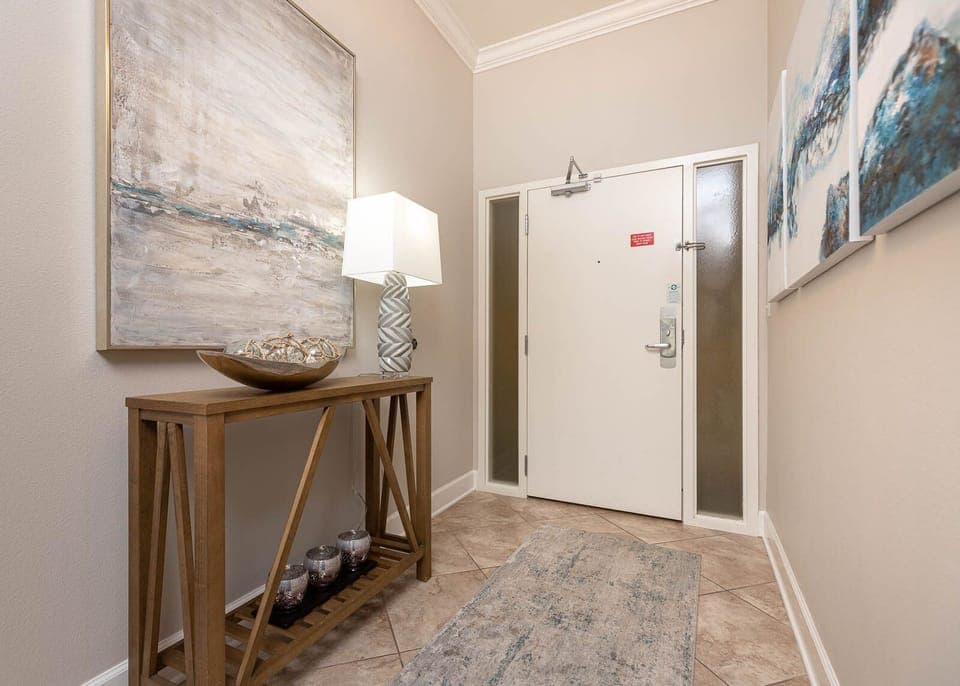 The entryway features a stylish console table, decorative artwork, and a soft rug, setting a warm tone for your stay