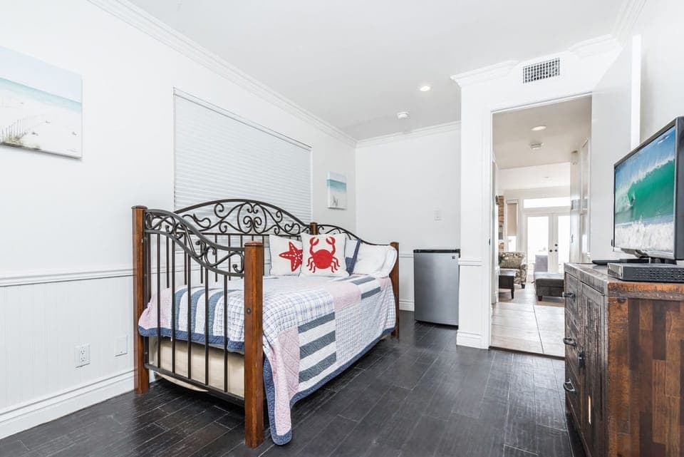 The fourth bedroom, conveniently situated on the first level adjacent to the second living room and garage area, features a twin bed, a twin trundle bed, and TV.
                