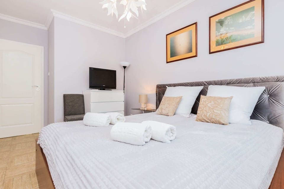 The main bedroom with a double bed, stylish bedding, and artwork on the walls. A bright and airy feel is created by the natural light from the windows.