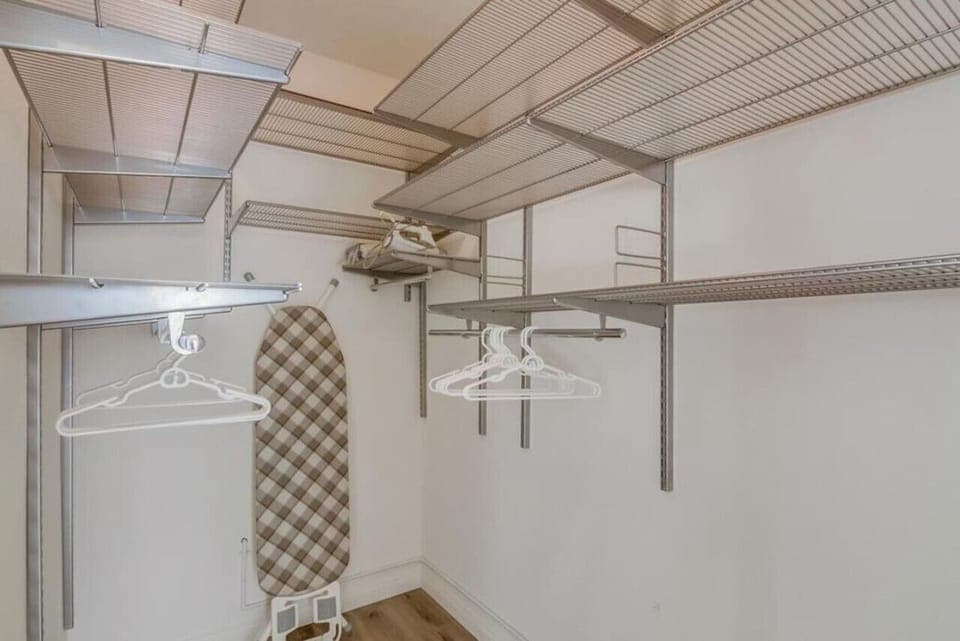 Walk-in closet - hangers, iron and ironing board.