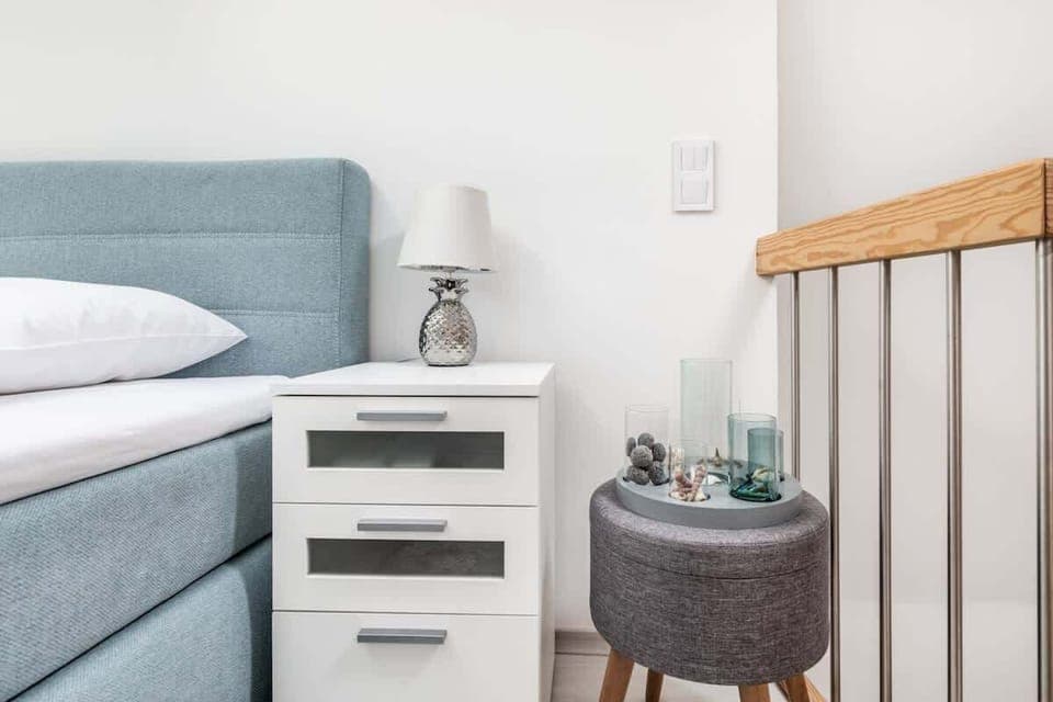 Close-up of bed and white bedside table with lamp. 