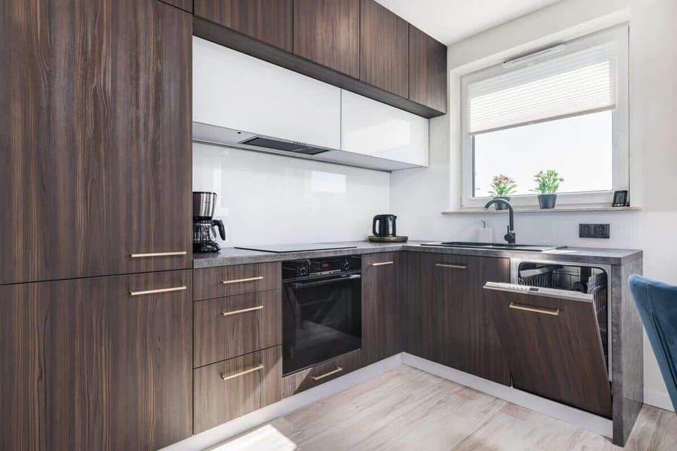 A sleek kitchen featuring wooden cabinets, white countertops, and modern appliances. The design is contemporary and minimalistic.