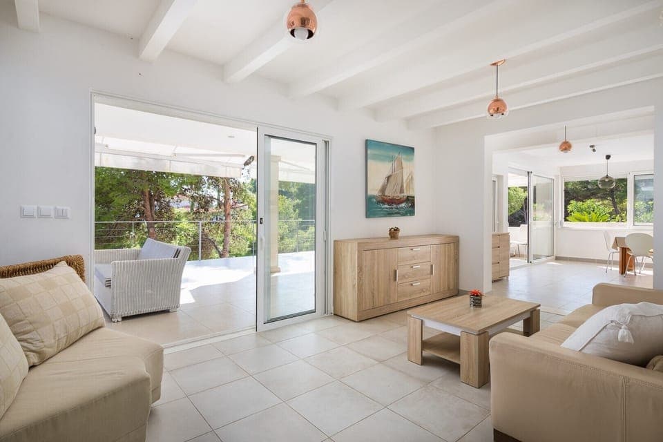 The living room of Croatia luxury villa Anemos with comfortable seating and sofa and direct access to the outdoor terrace with a view of the sea on the island of Hvar