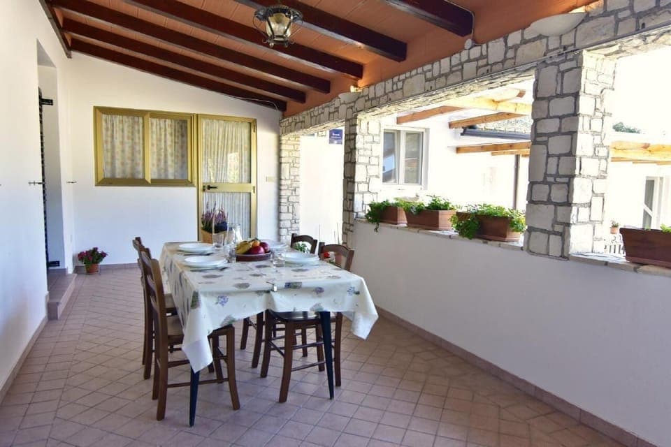 The large covered terrace furnished with dining table and chairs