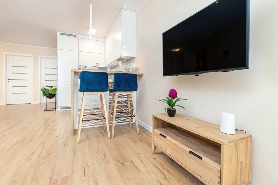 An open living space with a vibrant blue sofa set, small dining table, and light wood flooring, offering a cohesive and inviting setting.