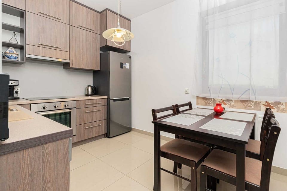 A compact kitchen with wooden cabinets and a small dining table, suitable for a cozy dining experience.