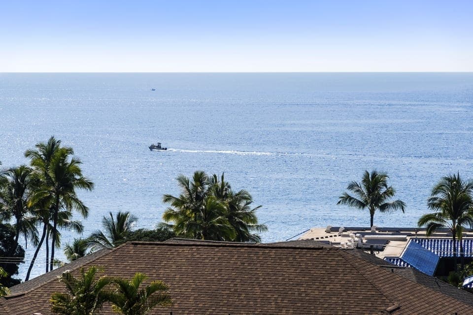 Expansive ocean view with passing boats framed by palms