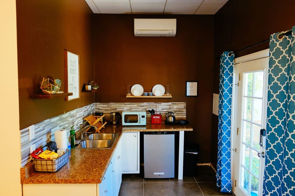 Kitchenette with coffee maker, microwave, dual hot plates, and dishware.