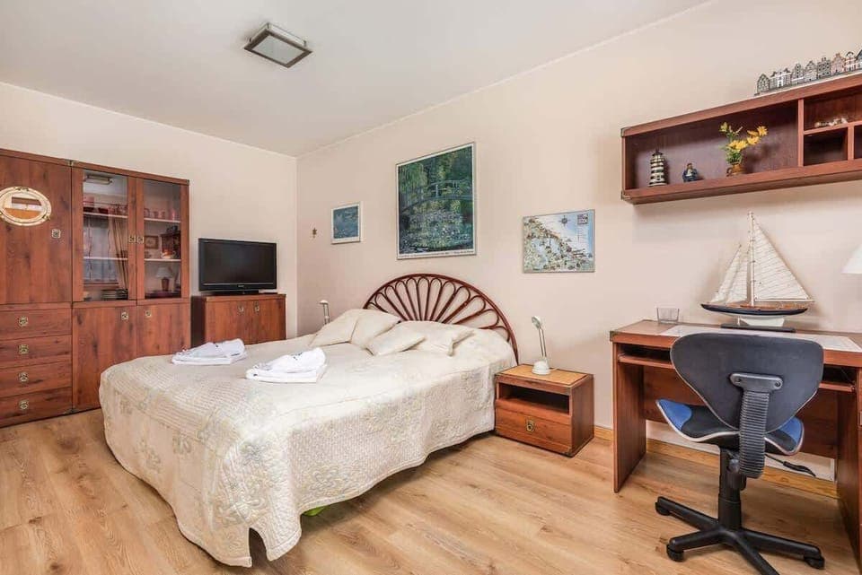 Cozy bedroom with a comfortable bed, wooden desk, and a chair, creating a perfect workspace.