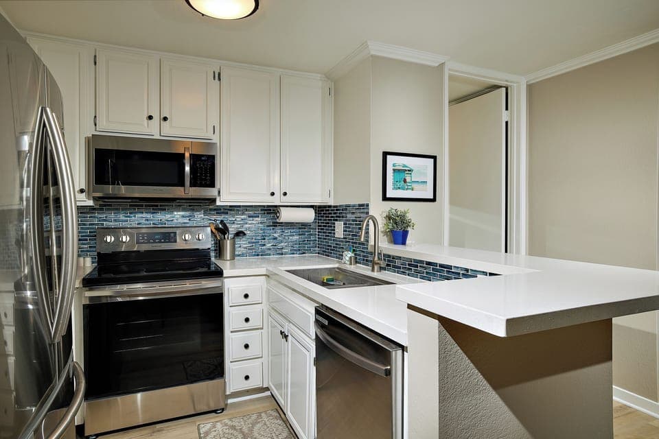 The kitchen has been remodeled with quartz countertops, stainless appliances, and a gorgeous designer backsplash.