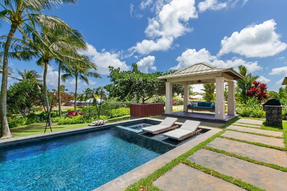 Lush landscaping adds privacy to the pool area with covered cabana and baja shelf lounge chairs