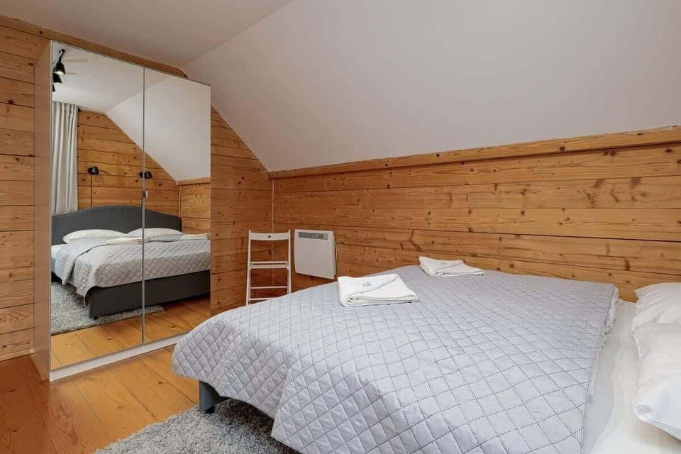 A cozy bedroom with wooden walls and ceilings, featuring a double bed and a wardrobe for a practical yet inviting design.