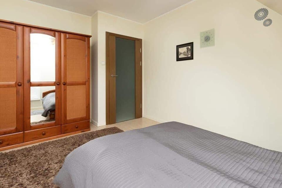 A bedroom featuring a bed under a slanted ceiling, with minimalistic decor and a warm ambiance.