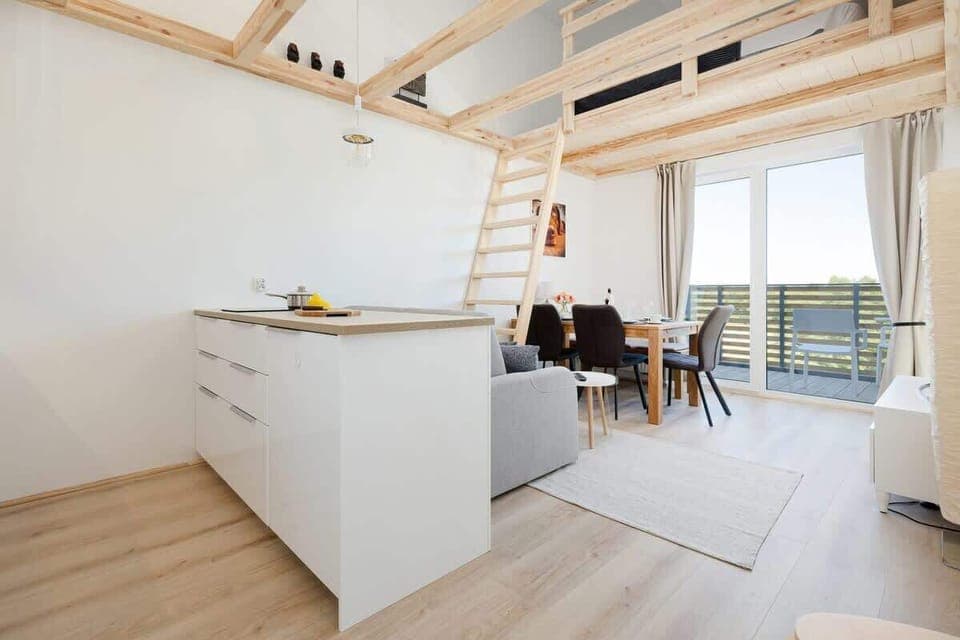 Bright Scandinavian-style interior with white and wood elements. A wooden staircase leads from the living room to the first floor.