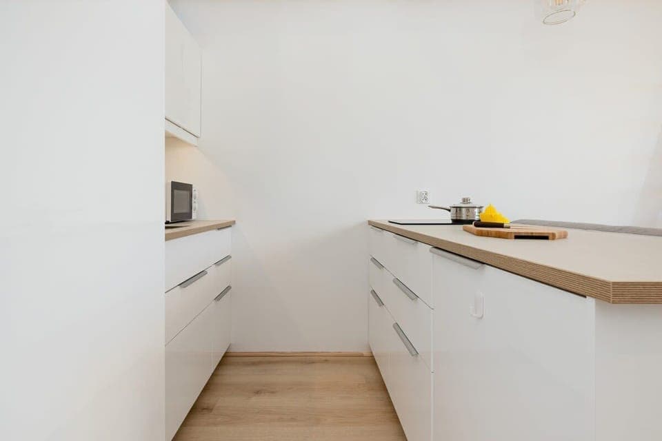 Functional kitchenette with white cabinets and wooden worktop.