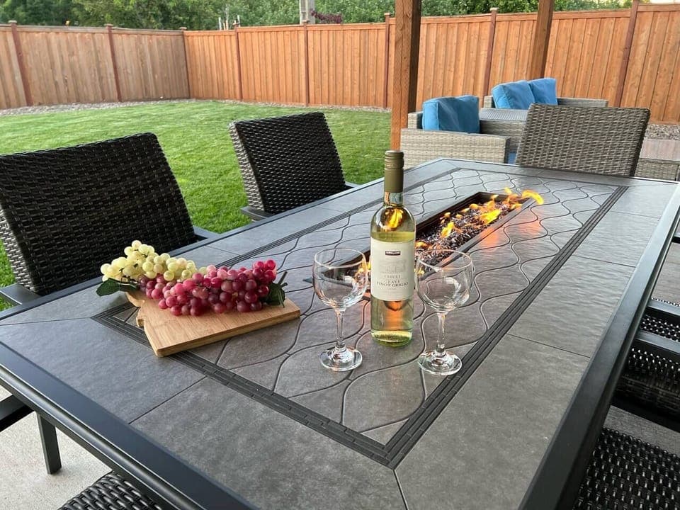 Enjoy a beautiful time outside with a fenced backyard, covered patio, green grass, and the table fire pit. 
