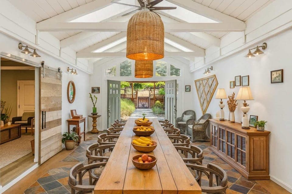 Gather around this sun-filled dining space with soaring beams, rustic wood accents, and warm lighting. A welcoming spot for shared meals, conversation, and unforgettable moments.
