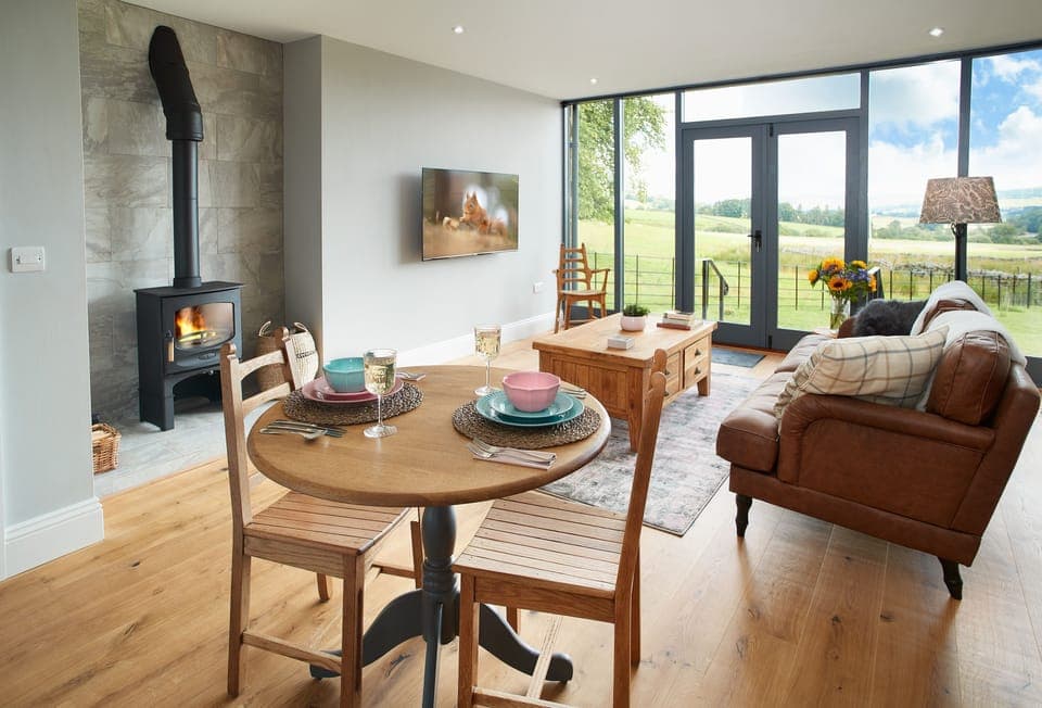 Ground floor: Open-plan living space with a cosy wood burning stove and doors leading out to open views of the rolling green hills