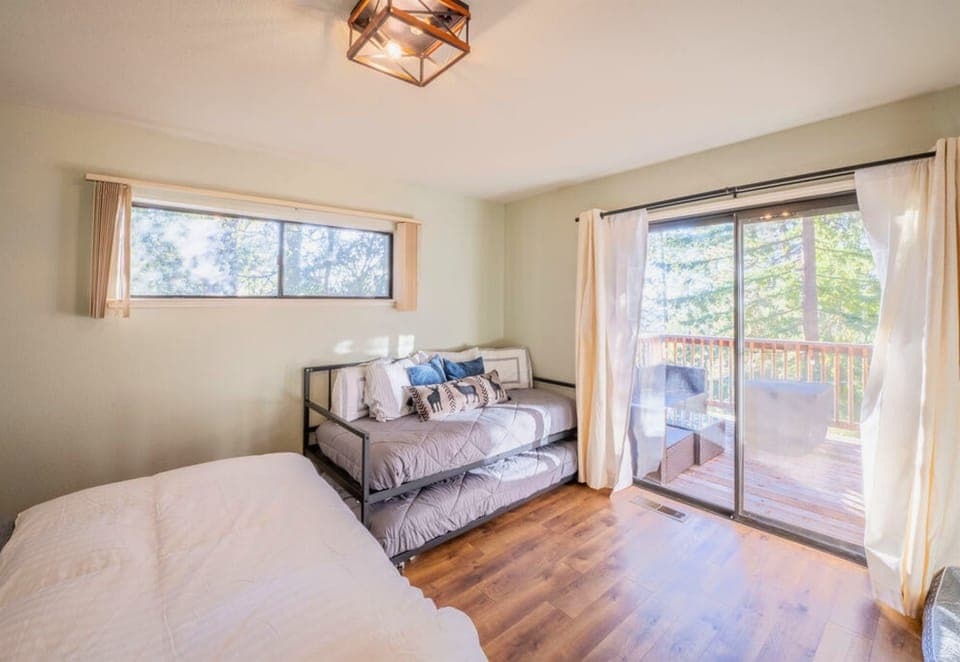 A light-filled bedroom featuring a plush bed and access to a sunny deck, promising relaxation in a serene cabin setting.