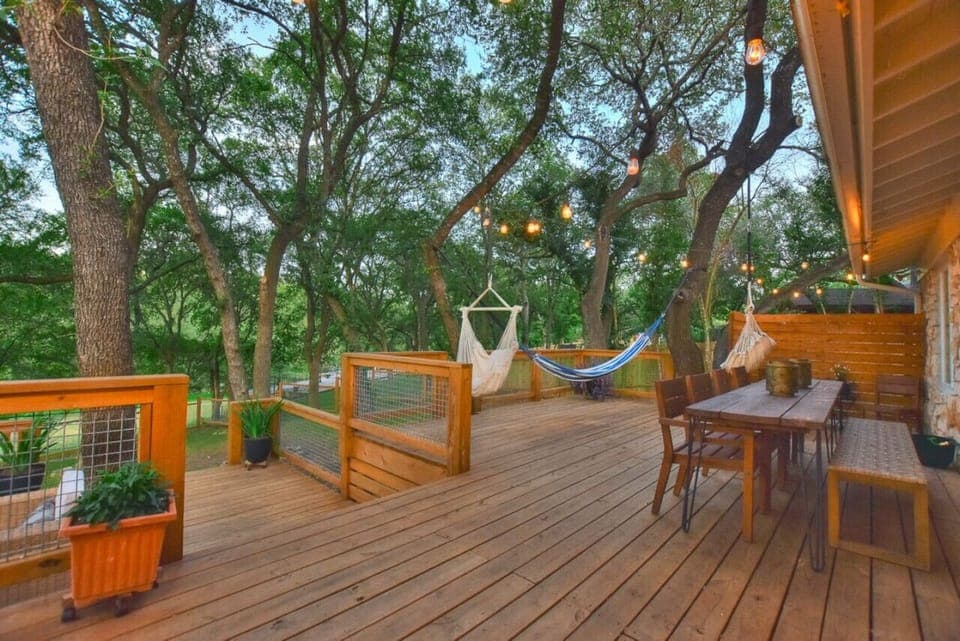 Expansive deck at Serenity on the San Gabriel with hammocks, string lights, and outdoor dining overlooking the river.