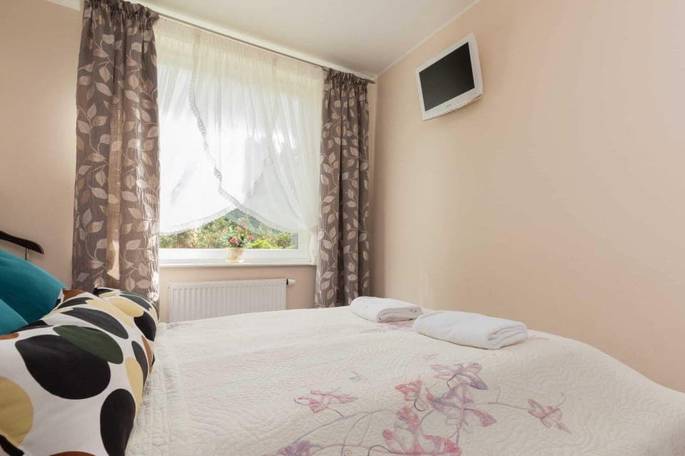  A cozy bedroom corner with a comfortable bed and natural light pouring in through the curtains.